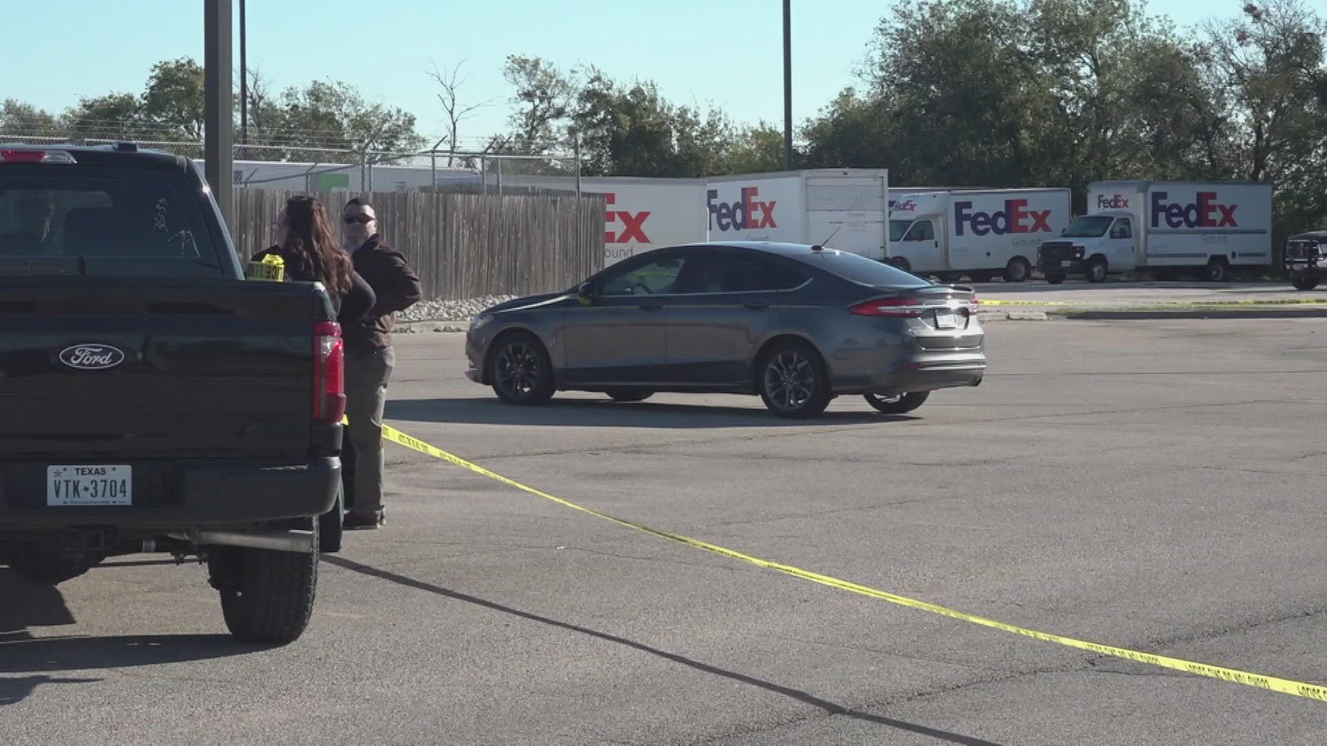 A shooting outside a FedEx parking lot caused two men to be injured, one of them is in police custody.