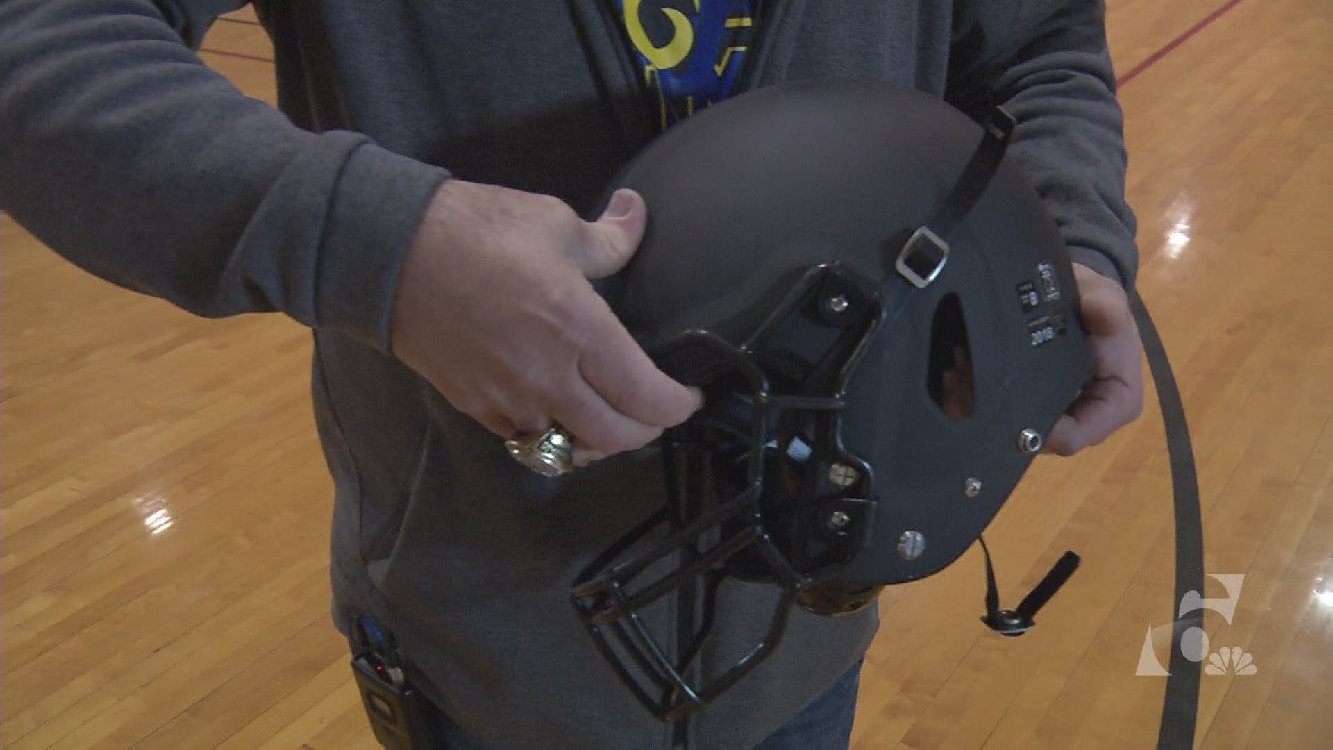 Mart HS assistant coach and equipment supervisor Mark Honeycutt explains the unique aspects of the Vicis helmet to Kurtis Quillin.